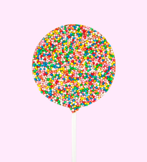 A chocolate freckle pop covered in multicolored sprinkles on a pink background, designed to look like a balloon.