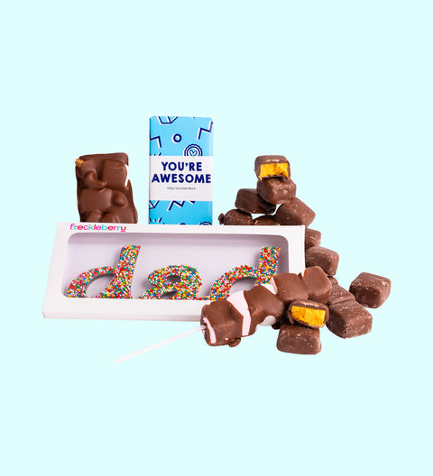 A dad gift box with an assortment of chocolate candies, including a milk chocolate block with 'You're Awesome' text, milk rocky road, honeycomb chocolate with marshmallows, and a chocolate with a Freckle Dad word on it, all presented with a 'You're Awesome' greeting card.