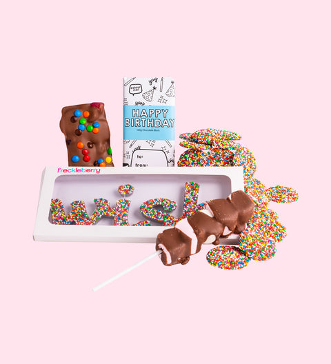 A gift box with an assortment of chocolate candies, including a milk chocolate message block, rocky road, milk chocolate freckles grab bag, mallow pop, and a wish word.