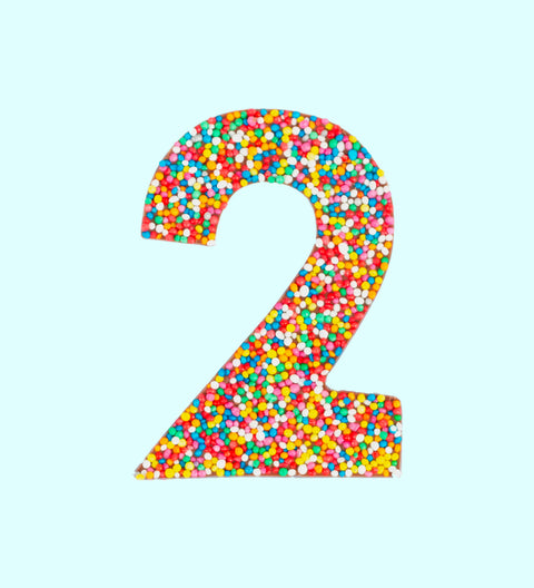 Belgian milk chocolate in the shape of the number 2, covered with multicolored sprinkles.