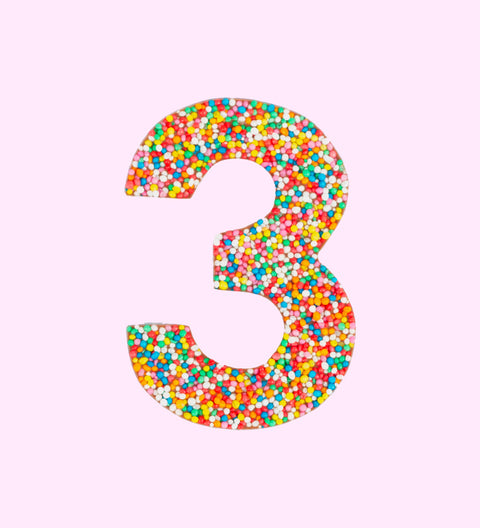 Belgian milk chocolate in the shape of the number 3, covered with multicolored sprinkles on a white background.