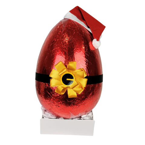 Huge 6kg Christmas egg. Red foil-wrapped chocolate egg with a yellow bow and Santa hat on a white background