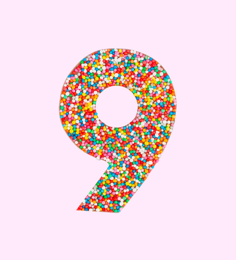 Belgian milk chocolate in the shape of the number 9, covered with multicolored sprinkles.