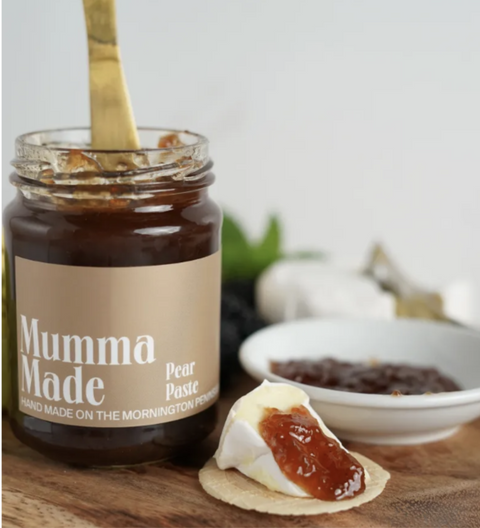 Jar of 'Mumma Made' pear paste with a spreadable sample on a cracker, set against a neutral background.