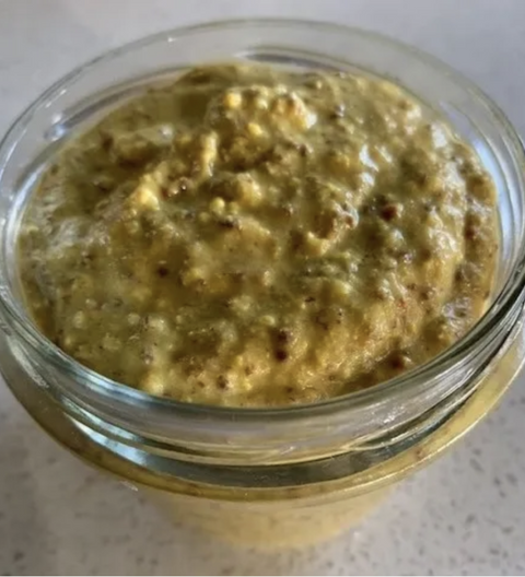 Jar of green spreadable food on a light background