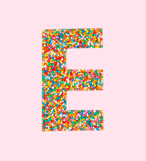 Belgian milk chocolate letter 'E' covered with multicolored sprinkles on a white background