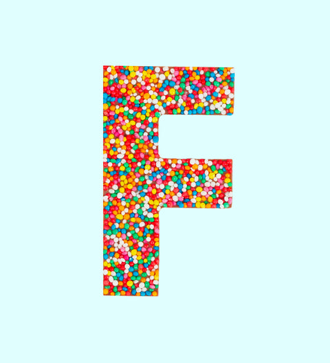 A milk chocolate letter 'F' covered with multicolored sprinkles.