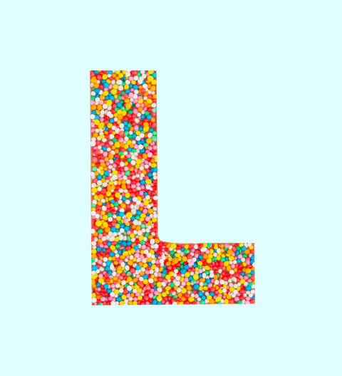 A chocolate letter 'L' covered in multicolored sprinkles on a white background.