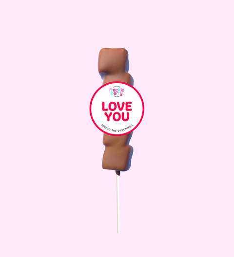Toy figure with a 'Love You' sticker on a pink background