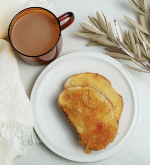 Two pieces of toast on a white plate with a cup of coffee and decorative elements on a light surface.