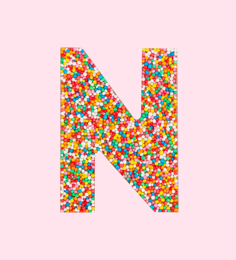 Belgian milk chocolate letter 'N' covered with multicolored sprinkles on a white background