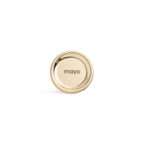 A tall, cylindrical white bottle with a brushed gold label disc at the bottom and a precision squeeze nozzle on the side. Mayonnaise
