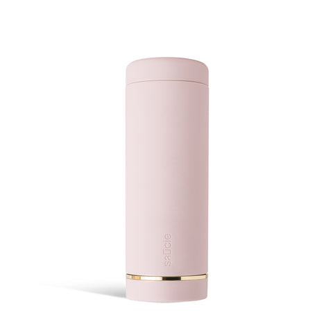 A tall, cylindrical pink condiment bottle with a brushed gold label disc at the bottom.