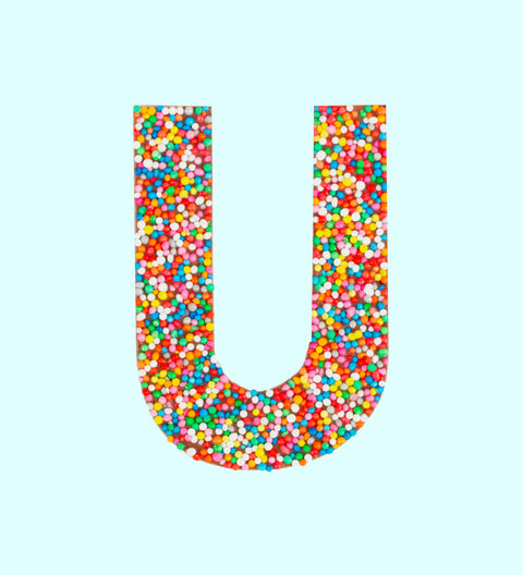 Belgian milk chocolate letter 'U' covered with multicolored sprinkles on a white background