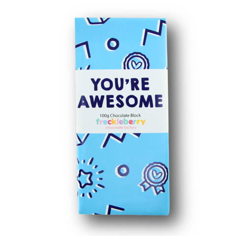 A wrapped 100g block of Belgian chocolate with a blue wrapper design featuring text 'YOU'RE AWESOME' and various symbols such as stars and hearts.