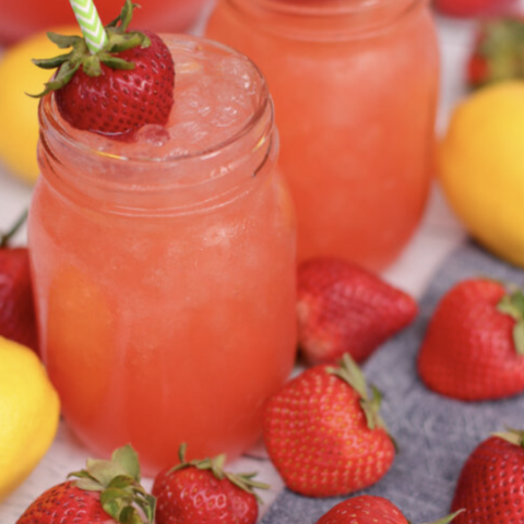 Fruit juice in a glass with strawberries and lemons on a table