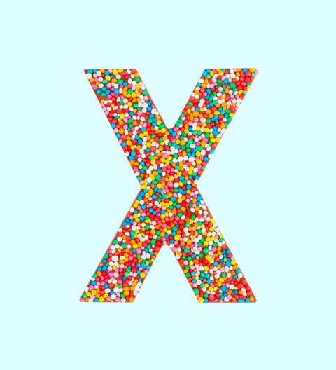 A milk chocolate letter 'X' covered in multicolored sprinkles on a white background