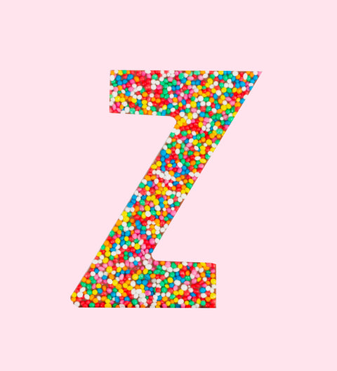 A milk chocolate letter 'Z' covered in multicolored sprinkles on a white background.