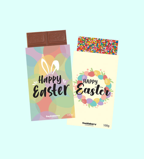 Two chocolate blocks with Easter-themed packaging, one with a 'Happy Easter' text in a colorful design and another with a floral wreath design. Both have '100g' weight indication.