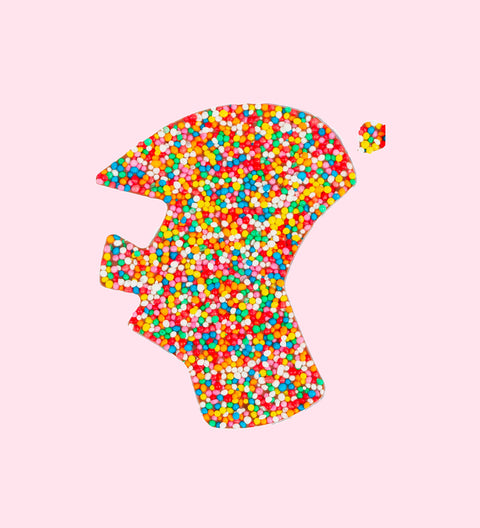 A chocolate piece in the shape of Australia map with multicolored sprinkles on it.