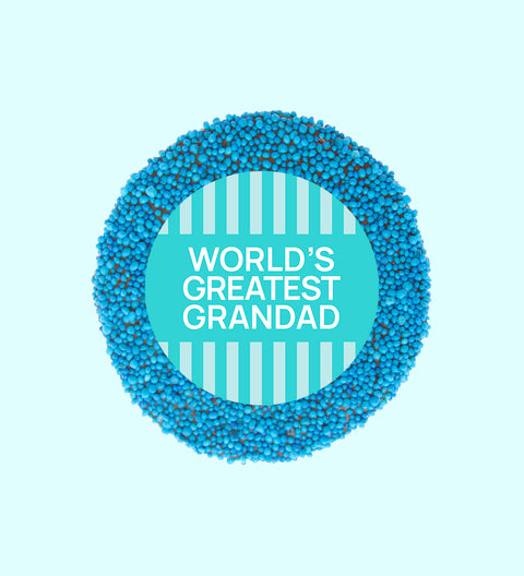 A chocolate freckle with 'WORLD'S GREATEST GRANDAD' written in the center, against a blue striped background.