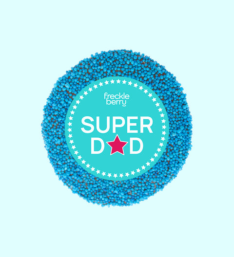 A chocolate freckle with 'Super Dad' text and a star sticker on top, against a blue background.