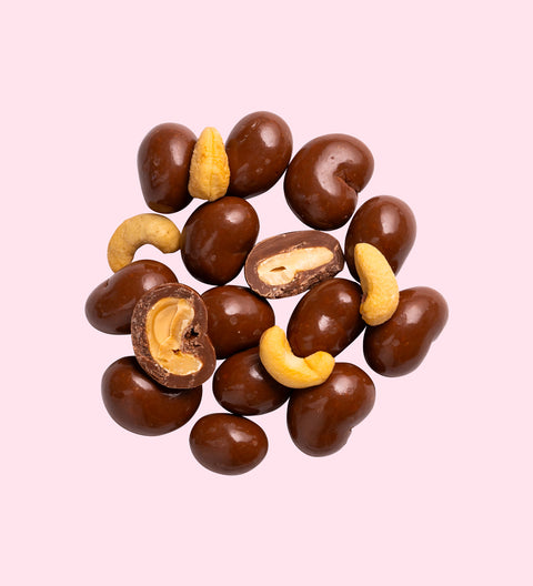 Milk chocolate coated cashew nuts close up
