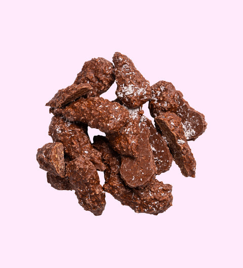 A pile of chocolate rough covered shredded coconut pieces dusted with powdered sugar.