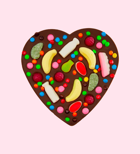 A heart-shaped chocolate pizza with various candies and lollies placed on it, on a white plate with the Freckleberry logo in the corner.