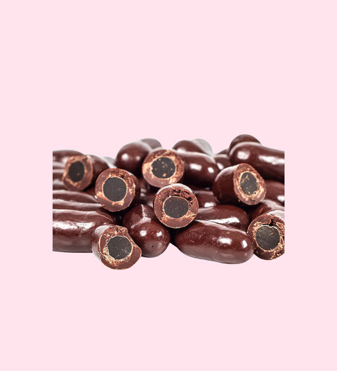 A collection of dark chocolate licorice bullets with the chocolate coating partially peeled back to reveal the licorice inside.