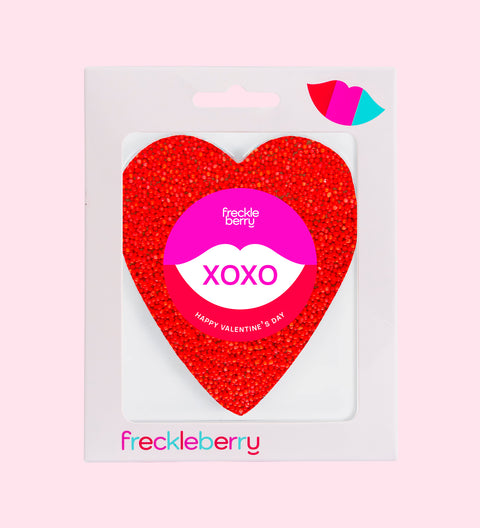 A red heart-shaped chocolate packaged with a 'XOXO' label and the brand 'freckleberry' at the bottom