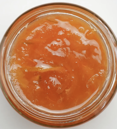 Jar of apricot jam with a white background