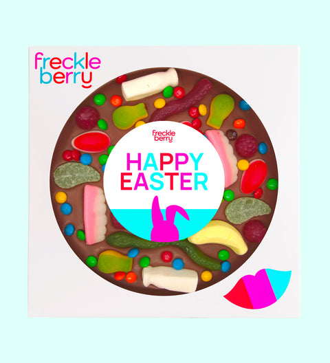 A giant chocolate pizza with various lolly toppings, including chocolate buttons and candies, with a text message in the center that reads 'YOU'RE A GOOD EGG'. The pizza is circular and has a 18cm diameter, with the product branding 'freckleberry' at the top.