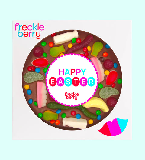 A giant chocolate pizza with various lolly toppings, including chocolate buttons and candies, with a text message in the center that reads 'YOU'RE A GOOD EGG'. The pizza is circular and has a 18cm diameter, with the product branding 'freckleberry' at the top.