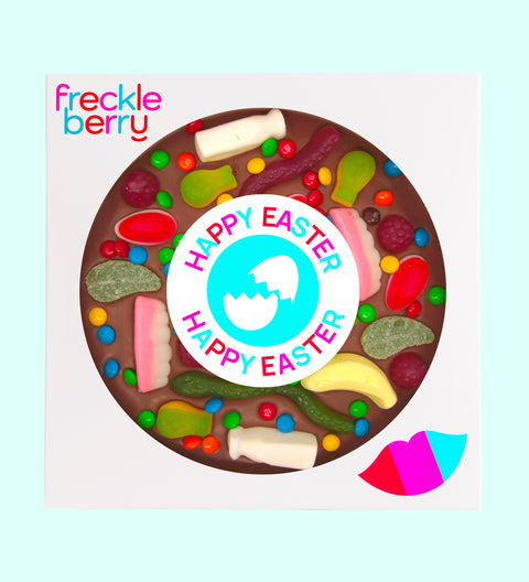 A giant chocolate pizza with various lolly toppings, including chocolate buttons and candies, with a text message in the center that reads 'YOU'RE A GOOD EGG'. The pizza is circular and has a 18cm diameter, with the product branding 'freckleberry' at the top.
