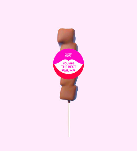 A marshmallow lollipop with a 'You are the best mum' text badge, covered in Belgian milk chocolate drizzle on a pink background.