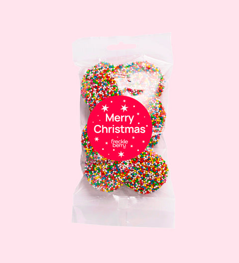 A clear packaging bag filled with multicolored chocolate freckles, sealed with a 'Merry Christmas' red label.