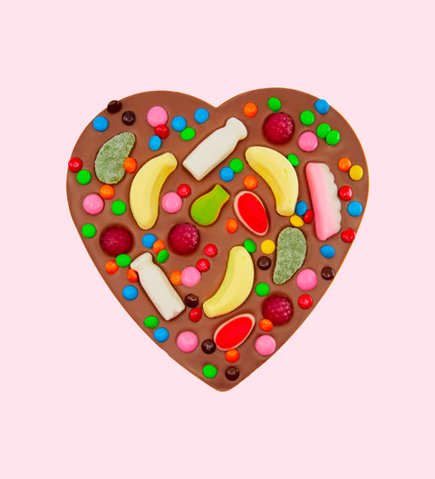 A heart-shaped chocolate pizza with various candies and lollies placed on it, on a white plate with the Freckleberry logo in the corner.