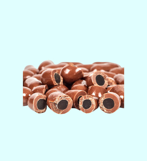 A collection of milk chocolate licorice bullets with the chocolate coating removed, revealing the black licorice inside.