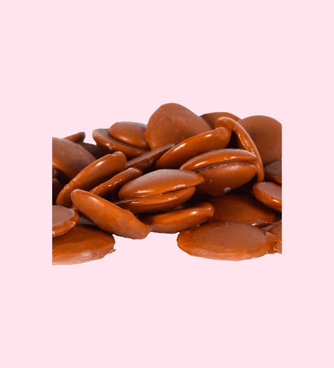 A pile of milk chocolate pastilles with a smooth and glossy texture.