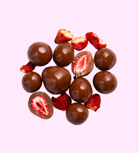 A collection of milk chocolate coated freeze-dried strawberries arranged on a white background, with some strawberries cut in half to show the interior.