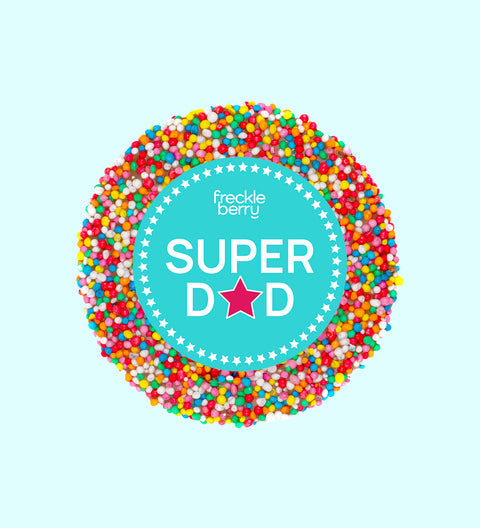 A chocolate freckle with 'Super Dad' text and a star sticker on top, against a blue background.