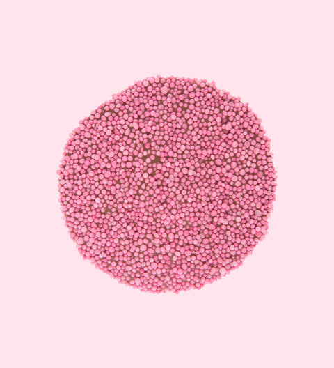A circular pink freckle candy on a pink background, individually wrapped.