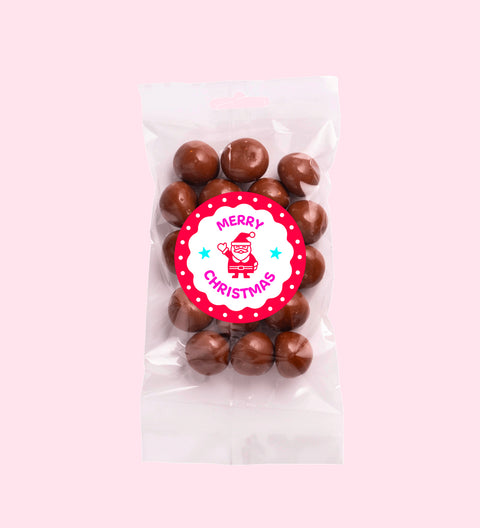 A clear plastic packaging containing milk chocolate coated raspberries with a red Christmas themed label that reads 'Merry Christmas'.