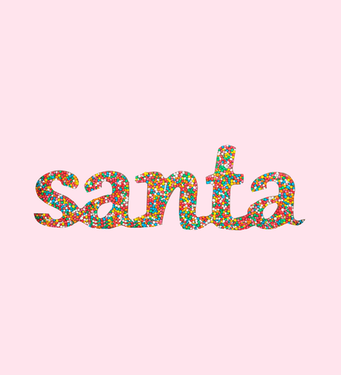 The word 'Santa' written in multicolored freckle-like chocolate pieces against a pink background.