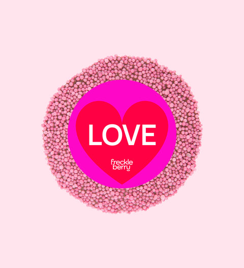 A colorful chocolate freckle with 'LOVE' text and the brand 'freckle berry' written on top, surrounded by multicolored sprinkles.