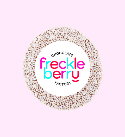 A single white chocolate freckle with a sprinkling of sugar on top, presented on a light background.