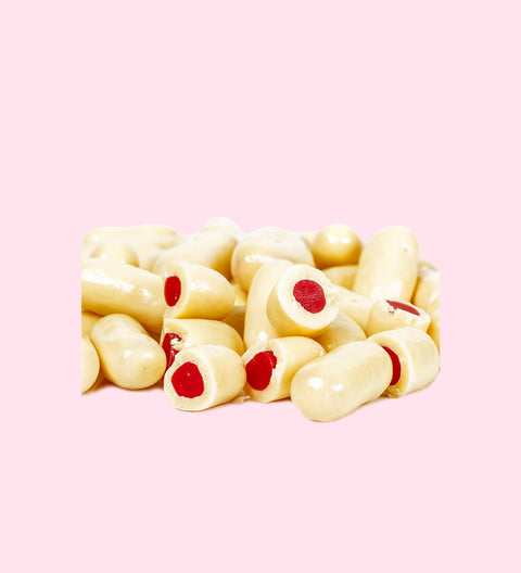 A group of white chocolate bullets with red raspberry fillings visible at the ends.