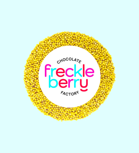 A single yellow milk freckle candy, 8cm in diameter, wrapped in a clear plastic sleeve.