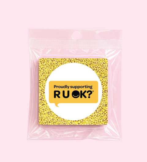 Packaged product with a yellow bead pattern and 'Proudly supporting RUOK?' logo on a pink background